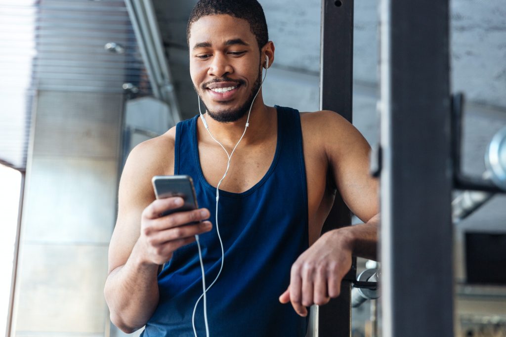 Smilling fitness man using smartphone in the gym