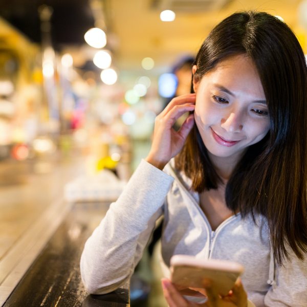 Woman reading news on cellphone in restaurant